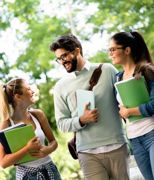 Happy university students friends studying with books at university